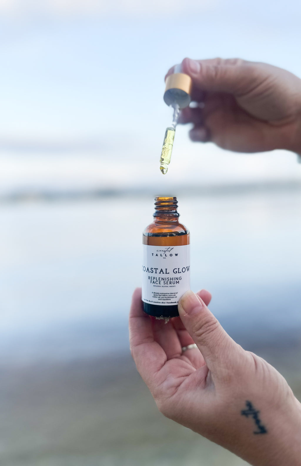 Hand holding a bottle of 'Natal Glow' with a dropper over a blurred background